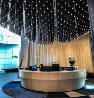 Warehouse 500 - Büroeinrichtung - München 43 Eleganter Empfangsbereich mit runder Theke, hängenden Lichtern und blühender Pflanze im modernen Design.