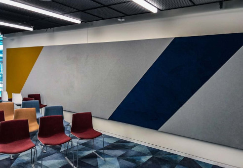 Warehouse 500 - Büroeinrichtung - München 40 Farbige Akustikwände in einem modernen Raum mit bunten Stühlen in Gruppen angeordnet.