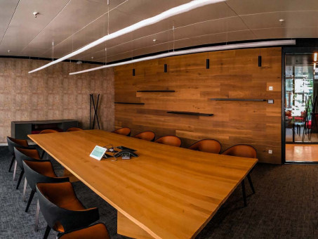 Warehouse 500 - Büroeinrichtung - München 35 Moderne Konferenzraum mit einem großen Holztisch, schwarzen Stühlen und hölzerner Wandverkleidung, ideal für Besprechungen.