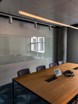 Warehouse 500 - Büroeinrichtung - München 14 Moderne Besprechungsraum mit einem großen Tisch, Stühlen und interaktivem Bildschirm in einem minimalistischen Büro.