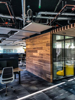 Warehouse 500 - Büroeinrichtung - München 6 Moderner Bürobereich mit Holzverkleidung, großen Fenstern und schwarzen Möbeln, optimale Lichtverhältnisse durch Tageslicht.