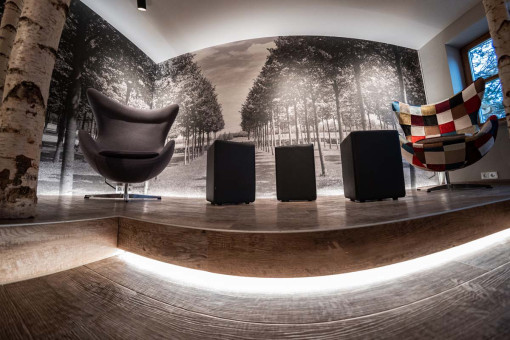 May Landschaftsbau - Büroeinrichtung - Feldkirchen 26 Moderne Lounge mit gepolsterten Sesseln und minimalistischen Hockern, umgeben von einem beeindruckenden Baum-Motiv an der Wand.