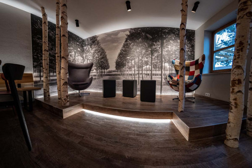 May Landschaftsbau - Büroeinrichtung - Feldkirchen 25 Moderne Sitzgelegenheit in einem stilvollen Raum mit Birkenstämmen und Schwarz-Weiß-Wandbild einer Allee.