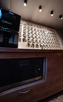 May Landschaftsbau - Büroeinrichtung - Feldkirchen 18 Küchenzeile mit Kaffeemaschine und Mikrowelle, im Hintergrund eine Wand mit zahlreichen Kaffeetassenhalterungen.