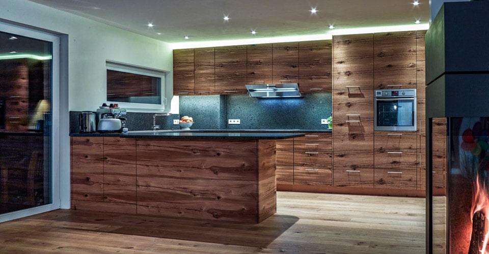 Schreinerküche mit Arbeitsplatte aus Stein und Holzfront und Holzofen