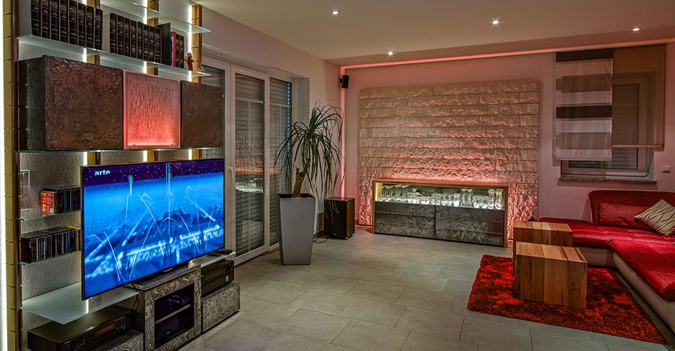 Wohnzimmer mit einem Fernseher auf einem modernen Regalsystem und roter Couch