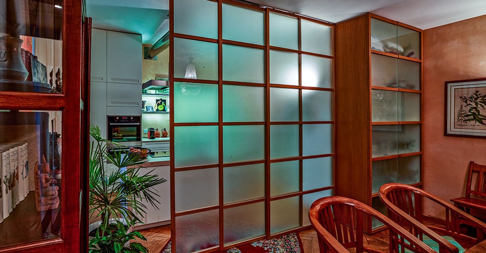 Große Schiebetüre aus Glas in Kachelform vor einer Küche