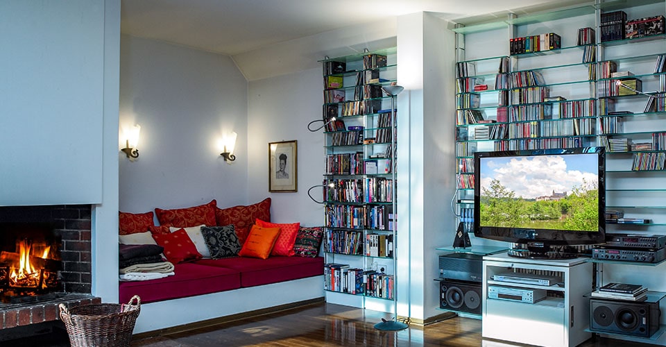 Wohnzimmer mit einem modernen Regalsystem an einer weißen Wand mit Glasböden und CDs