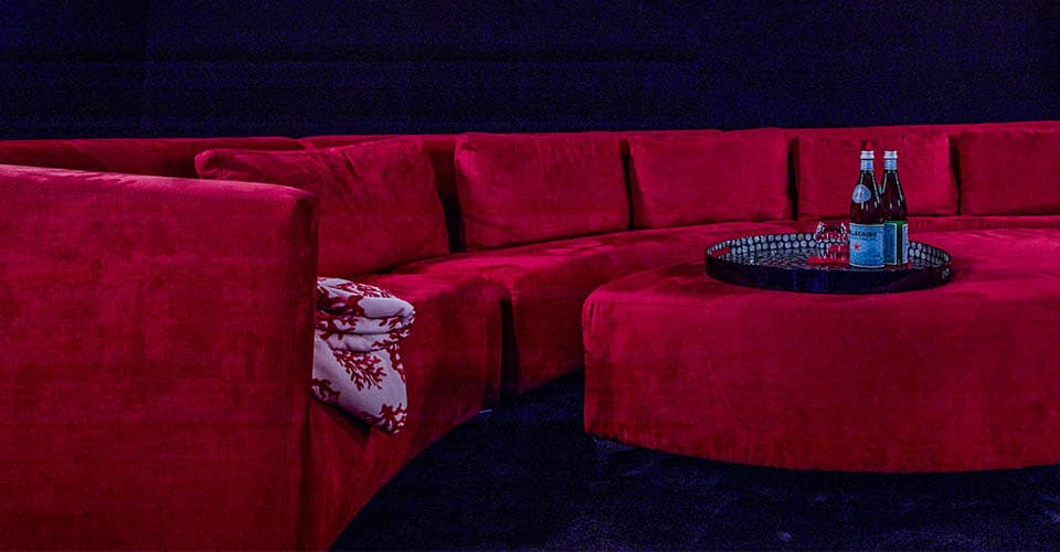 Große rote runde Couch mit kleinem rotem Tisch und Wasserflaschen