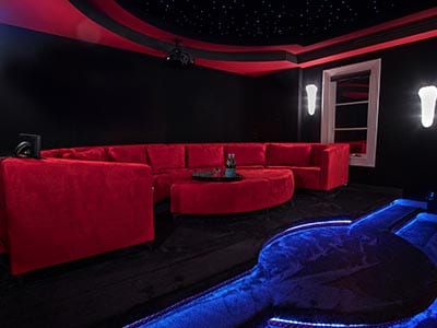 Heimkino mit einer großen roten Couch und blauem Teppich