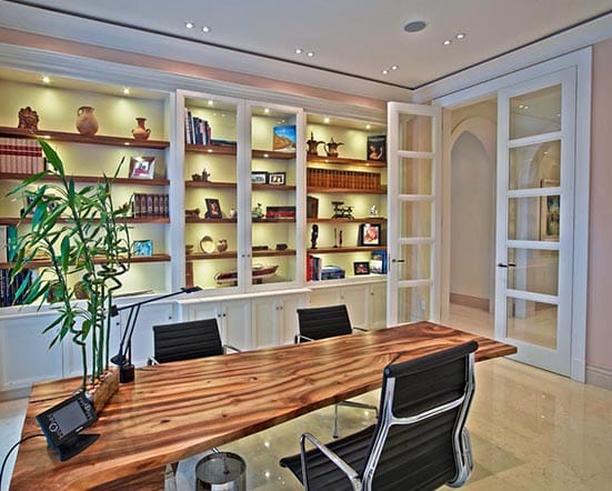 Inneneinrichtung eines Arbeitszimmer mit edlem Massivholztisch und klassischem Einbauregal mit Profilleisten vom Schreiner in München
