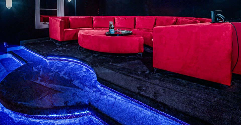 Große rote Couch in einem Heimkino mit blauer Beleuchtung auf blauem Teppich